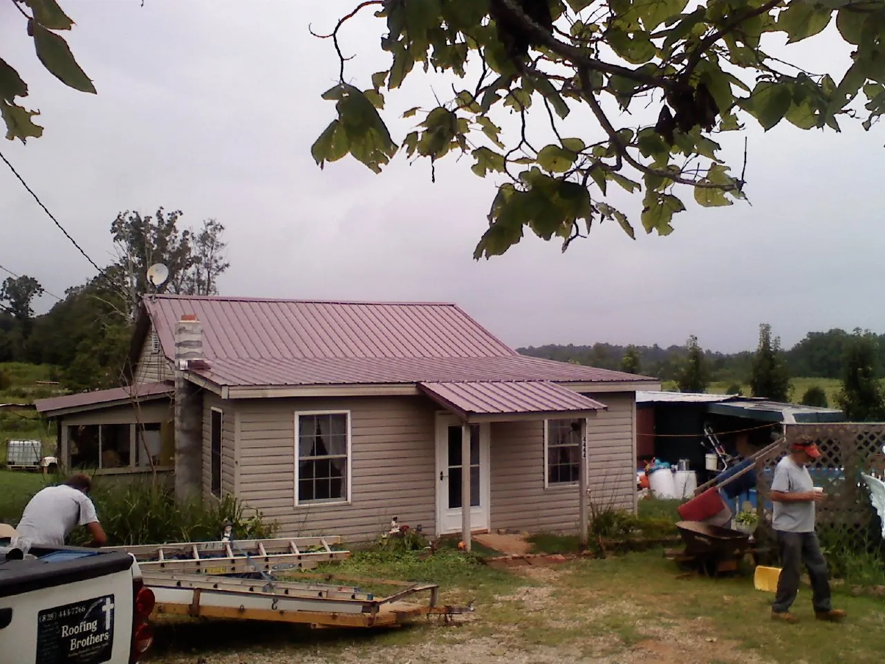 Crew finishing a mauve metal roof on a small farmhouse in Eastport