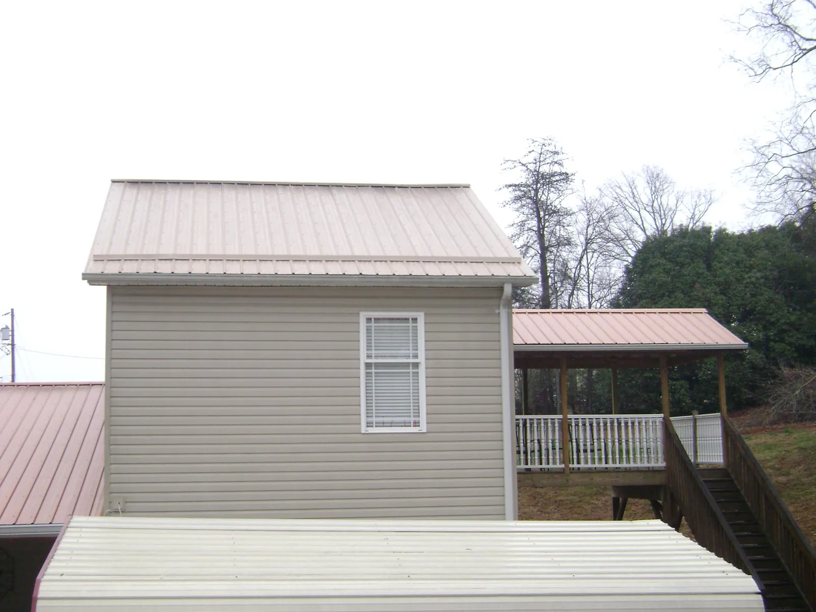 Tan metal roofs on a two story addition and attached porch, from a Roof Replacement job in Eastport